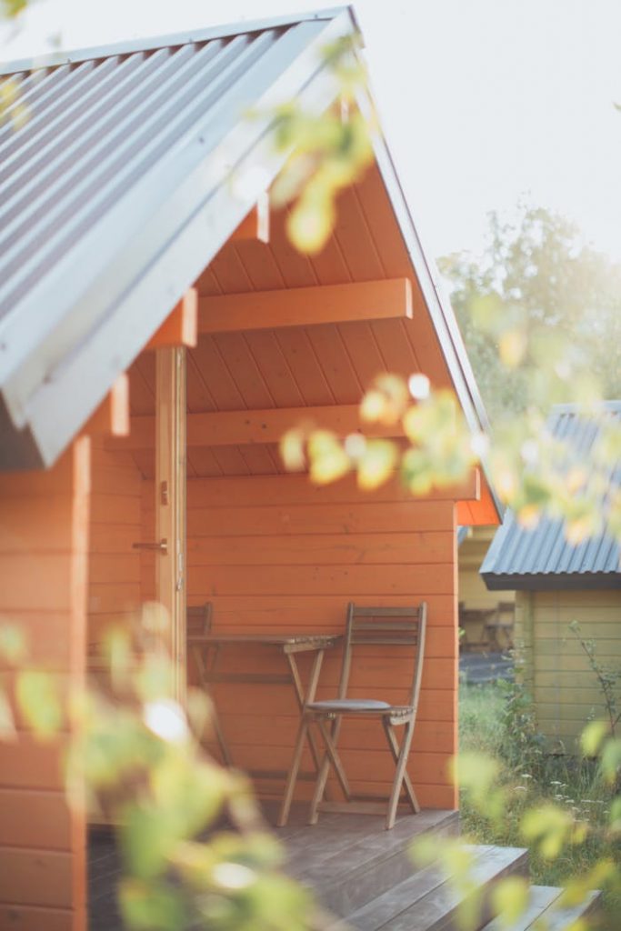 Charming wooden cabin exterior with a sunlit veranda, perfect for summer relaxation.